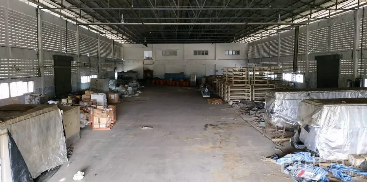 工厂 出租在Bang Pakong, Chachoengsao - 宽敞厂房内部，高钢结构屋顶与通风墙，摆放托盘和储物架。