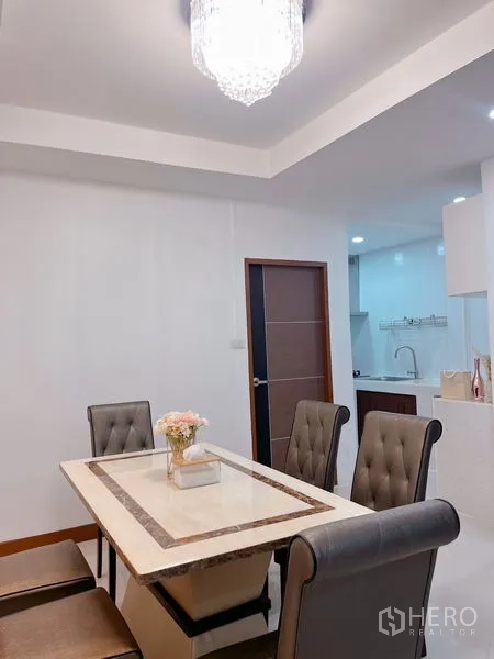 Townhouse for rent in Huai Khwang, Bangkok - Bright dining room with a marble-top table, tufted chairs and a crystal chandelier.