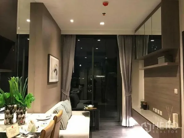 Condominium for rent in Watthana, Bangkok - Open-plan lounge and dining area leading to a balcony with night city views.