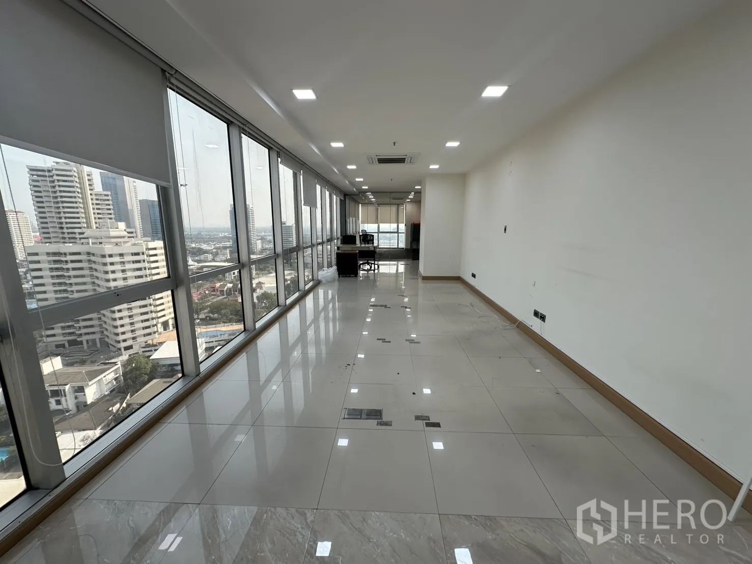 Office Space for rent - Long workspace with floor-to-ceiling windows and panoramic Bangkok skyline.