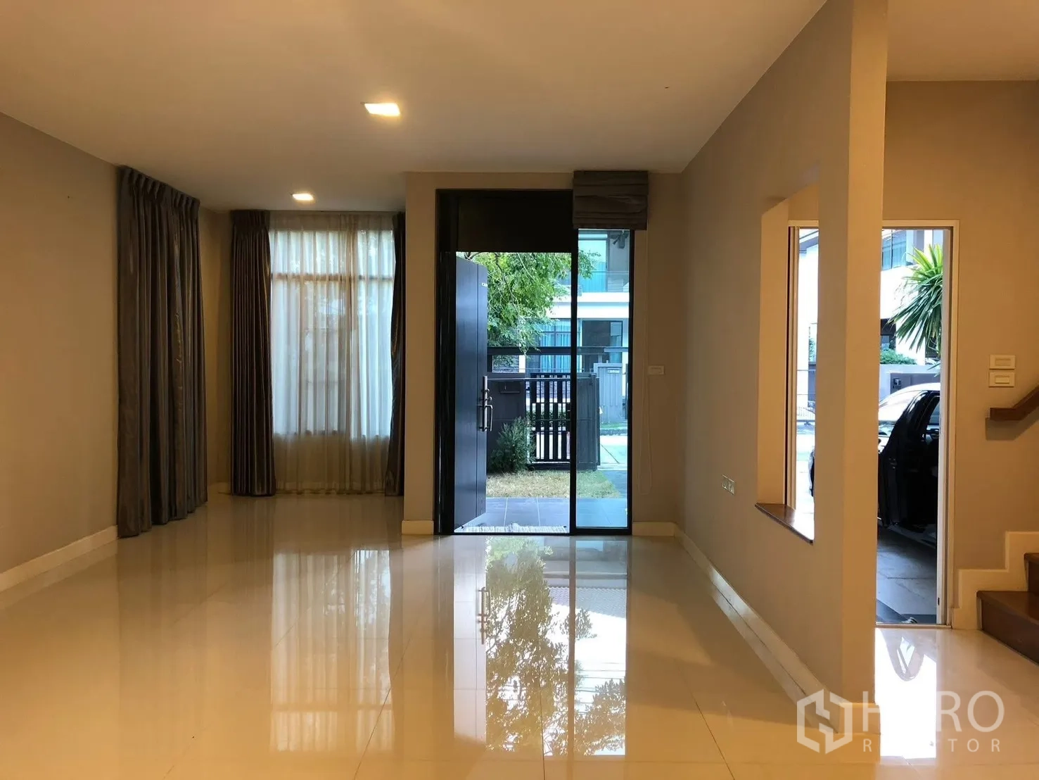 Detached House for rent in Prawet, Bangkok - Bright living room with glossy tile floor, large windows and front entry opening to a small garden.