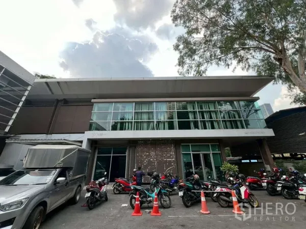 办公空间 出租在Watthana, Bangkok - 双层玻璃立面办公楼，门前有机车停车位与宽檐。