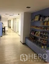 Office Space for rent in Khlong Toei, Bangkok - Hallway with display shelving and glass-front meeting rooms along a light wood floor.
