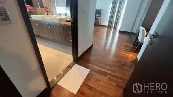 房间 出租在Pathum Wan, Bangkok - 走廊通向双台盆浴室和采光良好的卧室，木质地板光洁。