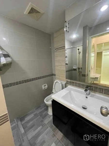 Condominium for rent - Modern bathroom with large mirror, sink cabinet and toilet.