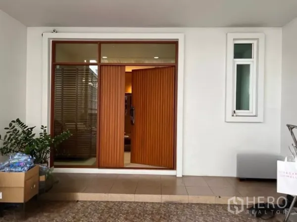 联排别墅 出租在Bang Kho Laem, Bangkok - 带顶车库与竖条木质双开入户门，旁有侧窗。