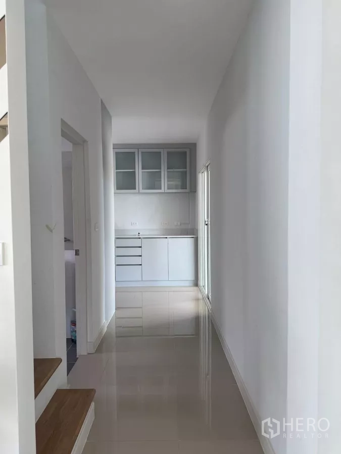 Detached House for rent in Bang Phli, Samut Prakan - Hallway with wooden stair treads leading to a pantry cabinet and sliding door.