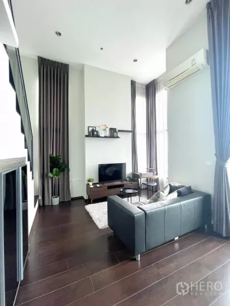 คอนโด ให้เช่าในWatthana, Bangkok - โซนนั่งเล่นกว้าง โซฟาหนังสีดำ พรม และเพดานสูง มุมมองจากทางเข้า