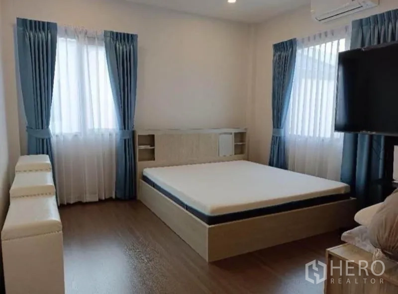 Detached House for rent - Airy bedroom with corner windows, blue curtains and a built‑in platform bed.