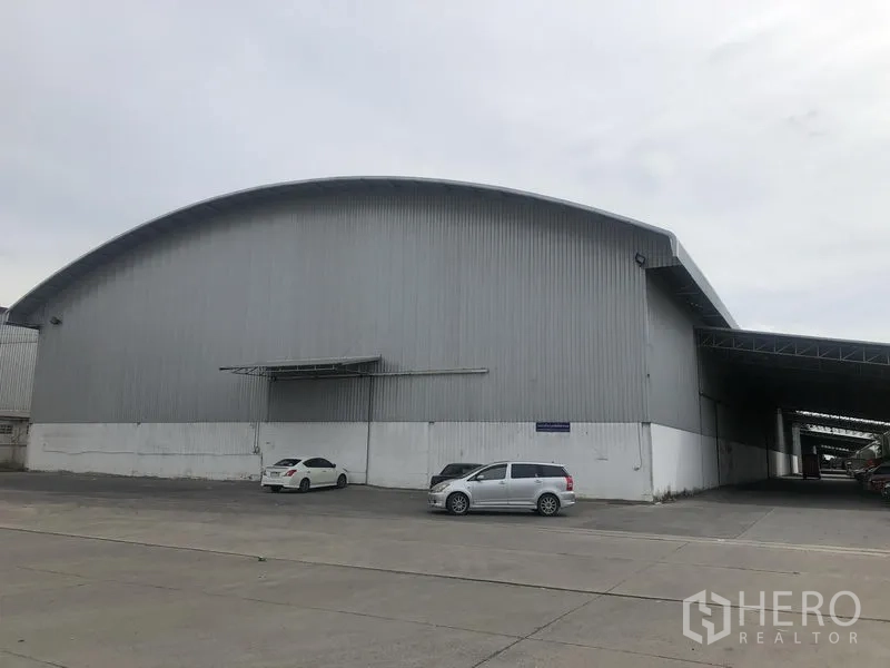 Warehouse for rent in Bang Pa-in, Phra Nakhon Si Ayutthaya - Front view of a large metal-clad warehouse with a curved roof and wide concrete yard.