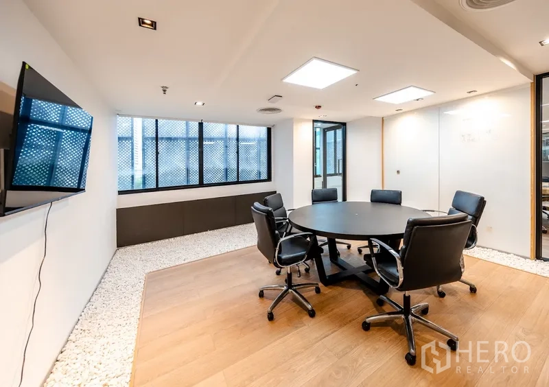 Office Space for rent in Bang Rak, Bangkok - Small meeting room with a round table, leather chairs, TV screen, and windows.