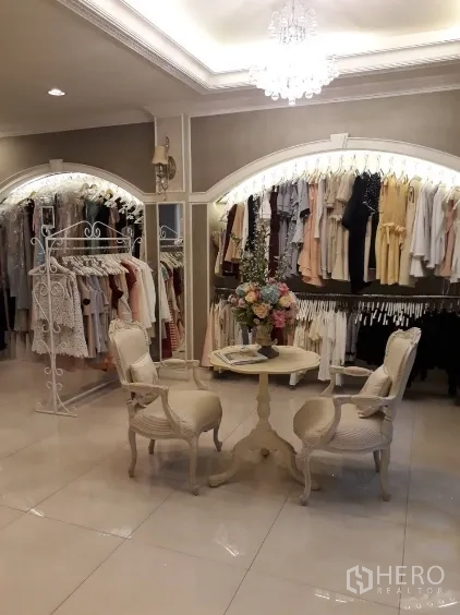 ตึกแถว for sale in Watthana, Bangkok - ห้องค้าปลีกมีราวแขวนเสื้อ โคมระย้า และโต๊ะกลมเล็ก.