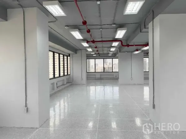 Office Space for rent in Bang Rak, Bangkok - Spacious columned office interior with large windows, LED panel lighting and glossy flooring.