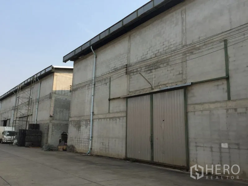 Warehouse for rent in Mueang Pathum Thani, Pathum Thani - Warehouse facade featuring a large sliding metal door along the service lane.