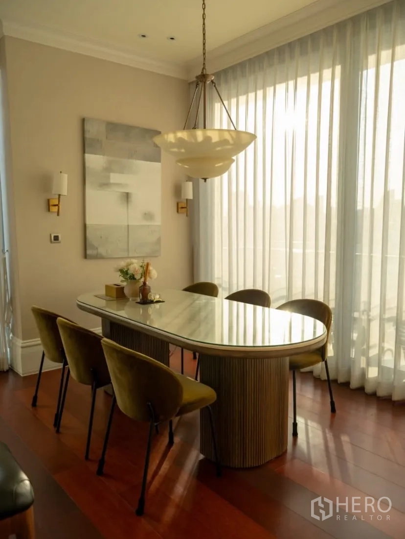 Condominium for rent or sale in Watthana, Bangkok - Dining room with oval marble-top table and pendant light by sheer curtains.