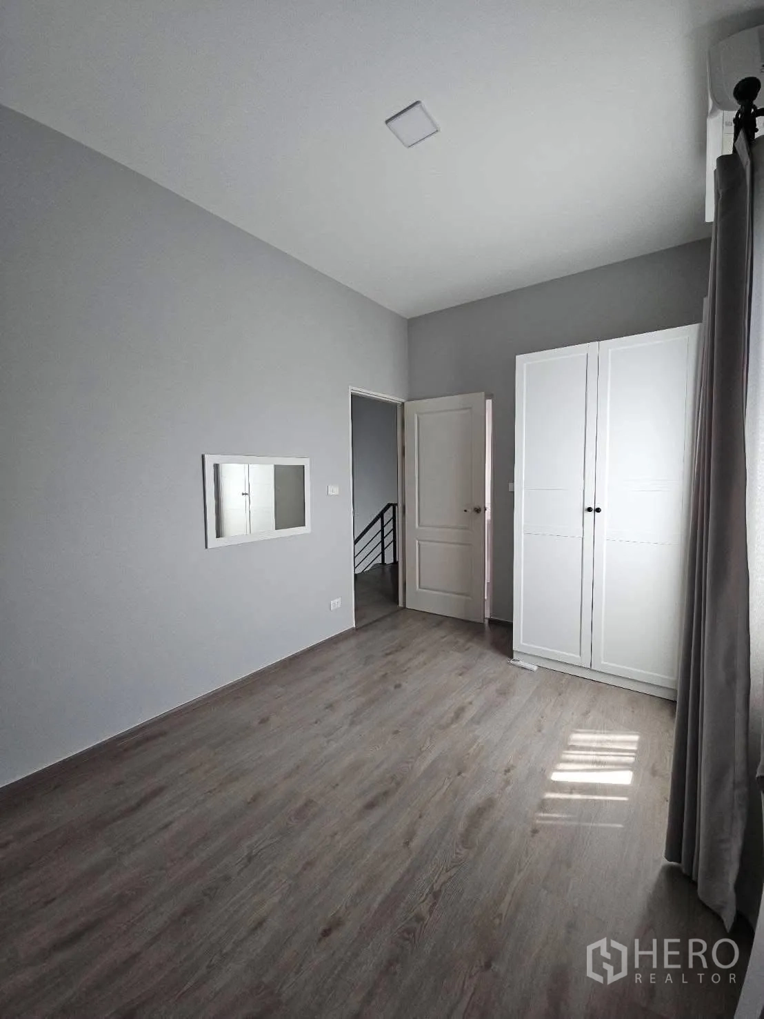 บ้าน for rent in Bang Phli, Samut Prakan - ห้องนอนสว่าง ผนังสีเทา พื้นไม้ ตู้เสื้อผ้าสีขาวและกระจกบานเล็ก