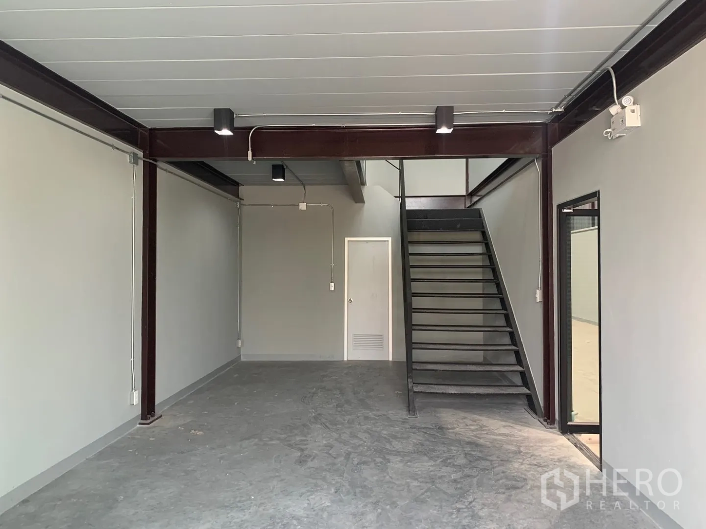 Warehouse for rent in Bang Phli, Samut Prakan - Ground level workspace with steel beams, staircase, and service door.