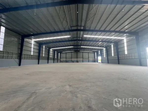 Warehouse for rent in Mueang Samut Prakan, Samut Prakan - Spacious high-ceiling warehouse interior with steel frames, skylights and a clear open floor.
