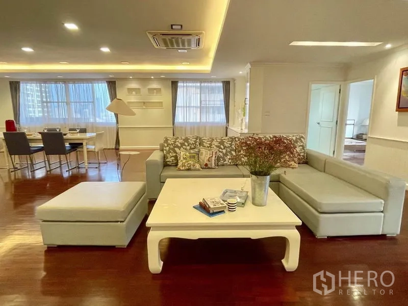 公寓 出租或出售在Watthana, Bangkok - 宽敞的客厅，L型沙发、茶几、木地板与嵌入式照明。