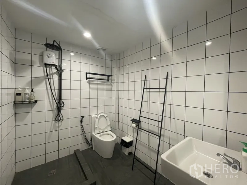 Home Office for rent or sale in Watthana, Bangkok - Modern bathroom with rain shower, wall-mounted sink and toilet on dark tiled floor.