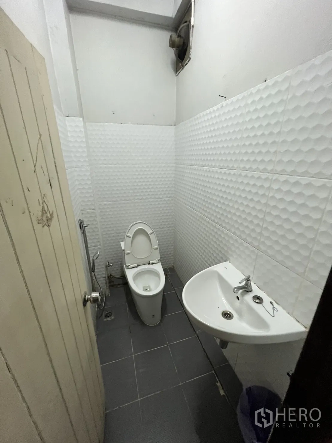 Shophouse for rent in Watthana, Bangkok - Compact restroom with white textured wall tiles and toilet.