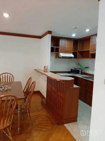 Apartment for rent in Watthana, Bangkok - Compact kitchen corner with hob, range hood, microwave and upper cabinets.