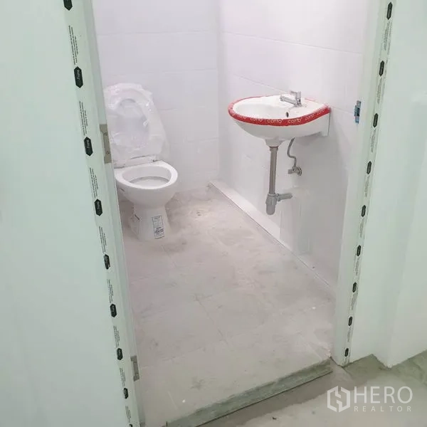 Warehouse for rent in Khlong Toei, Bangkok - Clean tiled restroom with toilet and wall‑mounted sink inside the warehouse.