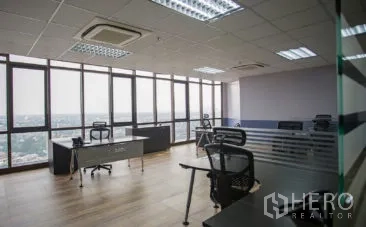 办公空间 出租在Khlong Toei, Bangkok - 转角工位区，环景曼谷视野，木地板、网面椅与顶灯照明。