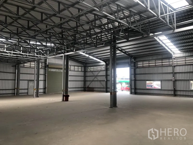 Warehouse for rent in Bang Yai, Nonthaburi - Open-plan storage hall showing steel trusses, skylight strips and a wide loading entrance.