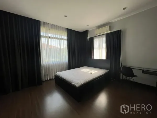 Detached House for rent or sale in Bang Kapi, Bangkok - Bright bedroom with double bed, full-length curtains and split-type air conditioner.