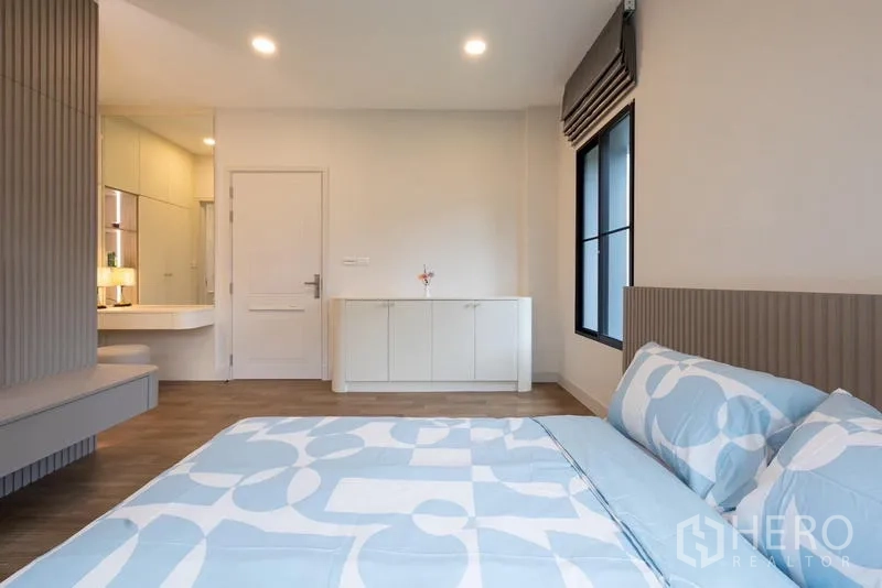 Detached House for sale in Saphan Sung, Bangkok - Bedroom with blue bedding, vanity corner and wood flooring.