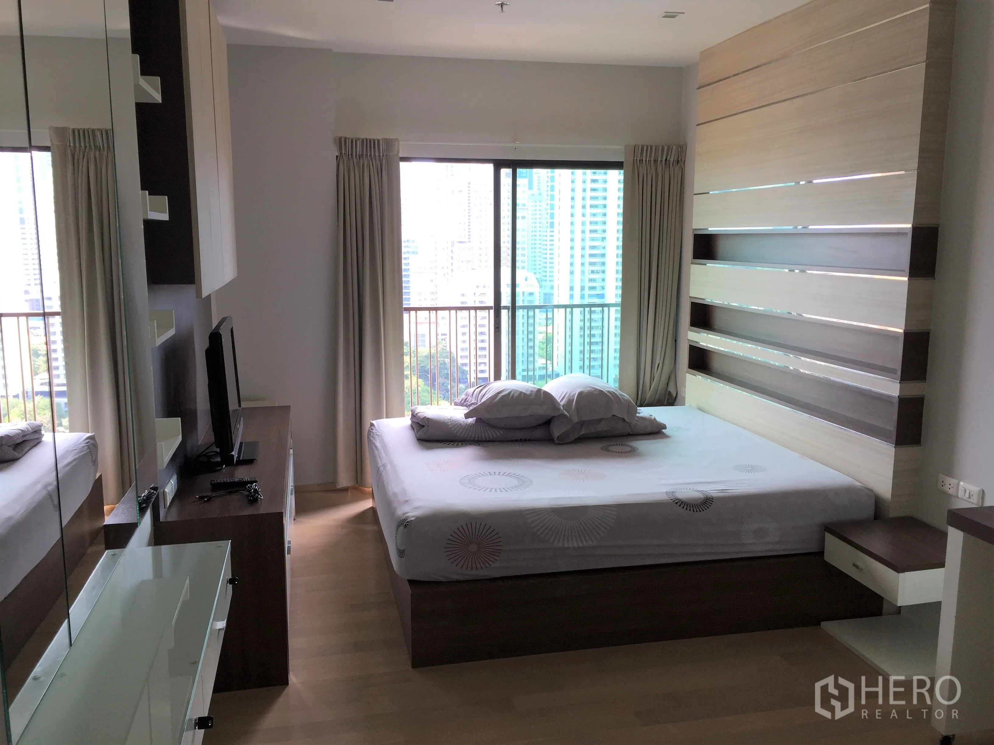 公寓 出租在Bangkok - 角落卧室，落地窗、电视柜，高层城市天际线景观。