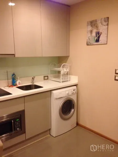 Condominium for rent in Ratchathewi, Bangkok - Modern kitchenette with hob, sink, microwave and front‑load washing machine.