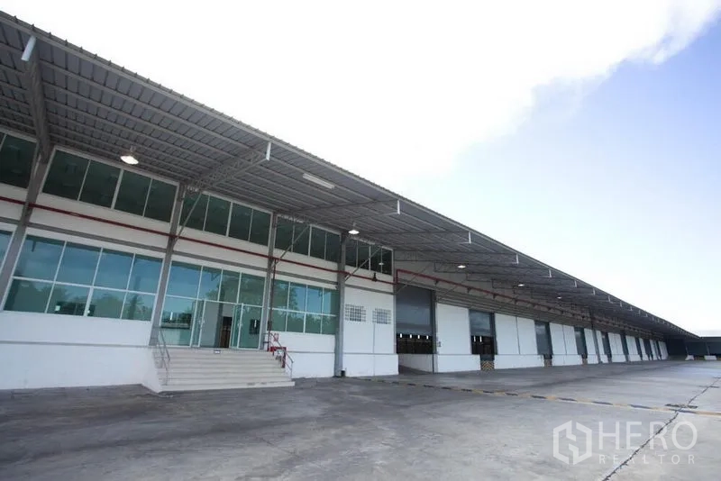 Warehouse for rent in Si Racha, Chon Buri - Warehouse exterior with covered loading dock, glass-front office and multiple truck bays.