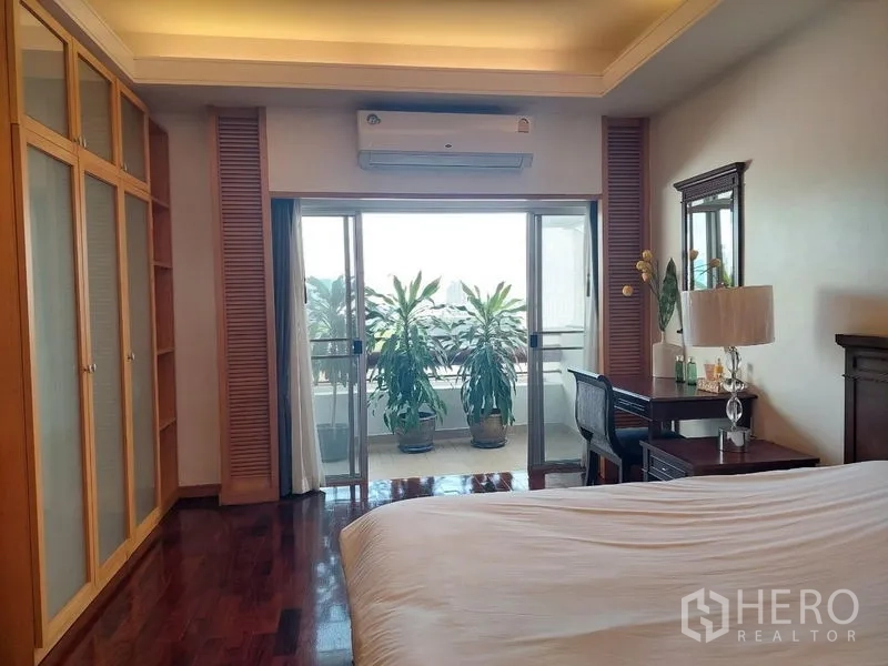 Apartment for rent - Master bedroom with built-in wardrobes, desk and sliding doors to a plant-lined balcony.