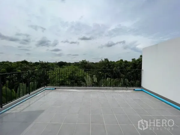 Townhouse for sale in Bang Kapi, Bangkok - Spacious rooftop terrace with railing overlooking green treetops and sky.
