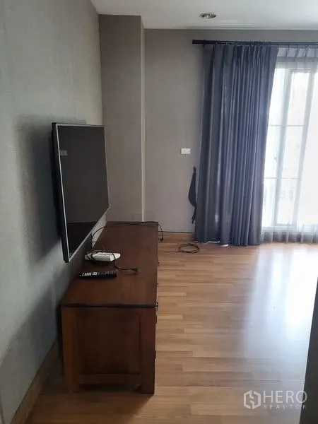 联排别墅 出租在Wang Thonglang, Bangkok - 卧室一角，墙挂电视、木柜与阳台窗帘