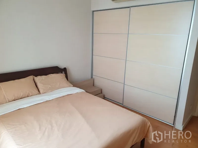 Condominium for rent or sale in Watthana, Bangkok - Second bedroom featuring a double bed, sliding built-in wardrobe and light wood flooring.