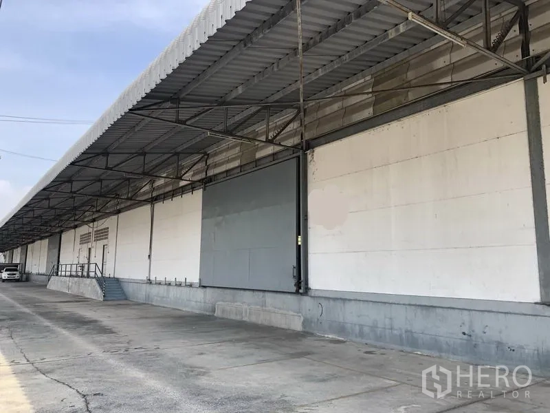货栈 出租在Khlong Luang, Pathum Thani - 带雨棚的装卸月台一侧视角，配有坡道与台阶，沿线为卡车通道。