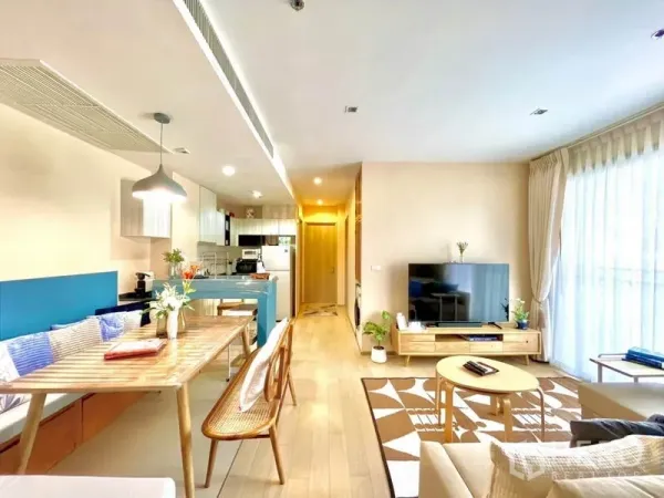 Condominium for rent or sale in Watthana, Bangkok - Dining nook with built‑in bench and wooden table facing the open kitchen and lounge.