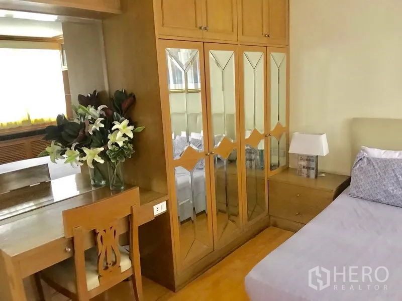 公寓 出租在Watthana, Bangkok - 卧室一角设镜面衣柜、梳妆台与床头灯。