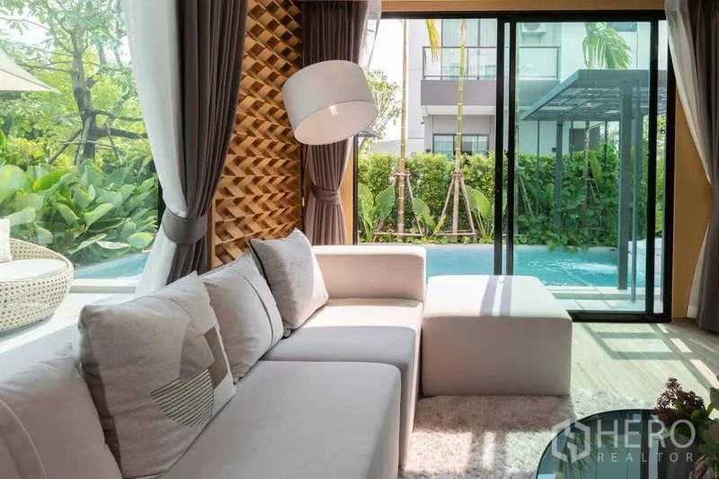 独立式住宅 出租或出售在Lat Krabang, Bangkok - 客厅L形沙发，推拉门直通私家泳池与花园。