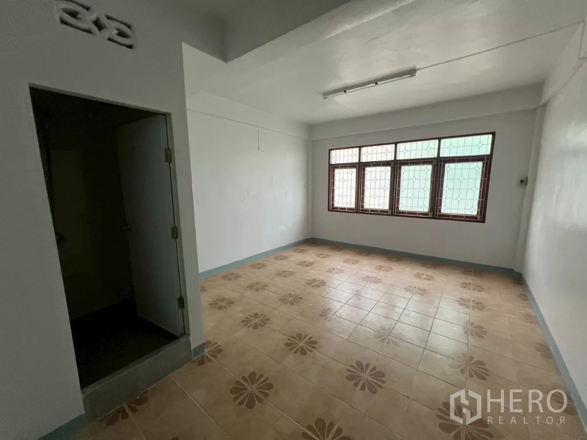 Shophouse for rent in Khlong Toei, Bangkok - Bright room with patterned ceramic floor tiles, wide front windows and an ensuite door.