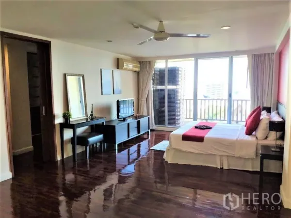 Condominium for rent in Bang Rak, Bangkok - Large master bedroom with ceiling fan, TV console and sliding doors to a balcony with city views.