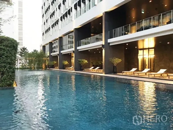 คอนโด ให้เช่าในPathum Wan, Bangkok - สระว่ายน้ำของคอนโดพร้อมที่นอนอาบแดด ข้างอาคารสมัยใหม่