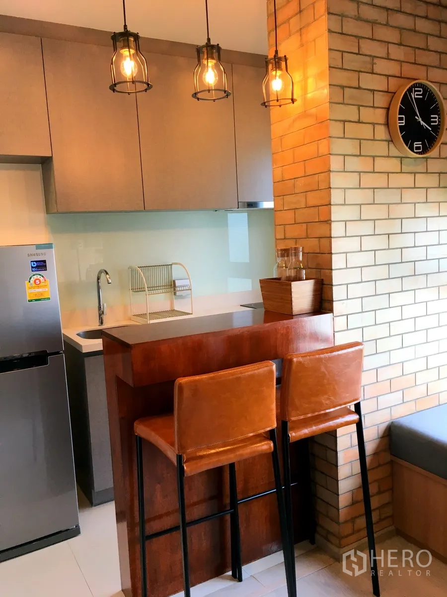 Condominium for rent in Khlong Toei, Bangkok - Compact kitchen with breakfast bar, pendant lights, fridge and sink