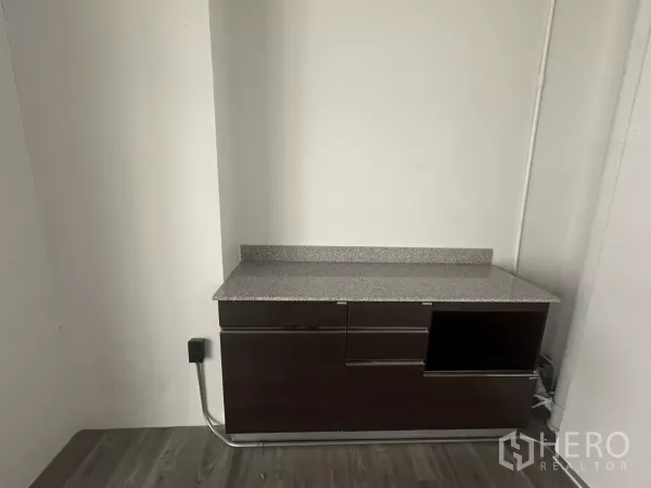 Retail Space for rent - Built-in pantry cabinet with a granite countertop against a white wall inside the retail unit.