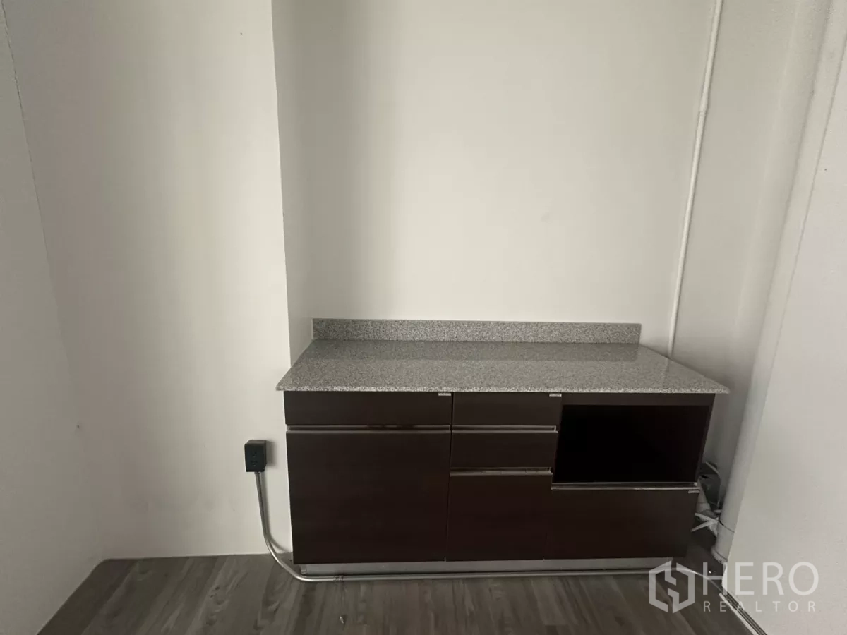 Retail Space for rent - Built-in pantry cabinet with a granite countertop against a white wall inside the retail unit.