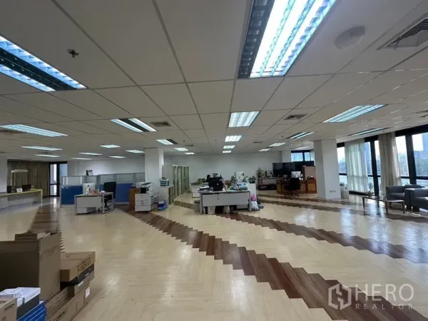 办公空间 出租在Khlong Toei, Bangkok - 大面积开放办公区，网格吊顶与荧光灯，整排窗户可欣赏湖景与天际线。