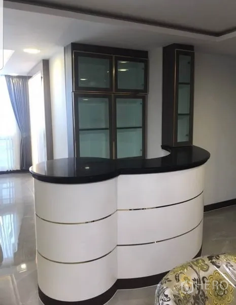 Condominium for rent in Khlong Toei, Bangkok - Curved home bar with black countertop and glass display cabinets.